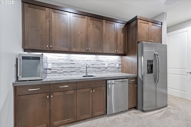 kitchen with a sink, appliances with stainless steel finishes, decorative backsplash, light colored carpet, and dark brown cabinets