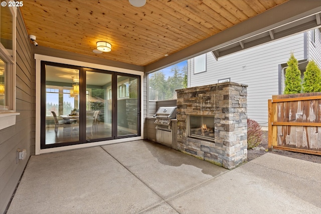 view of patio with area for grilling and an outdoor stone fireplace