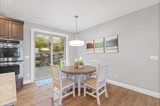 dining area with baseboards and light wood-style flooring