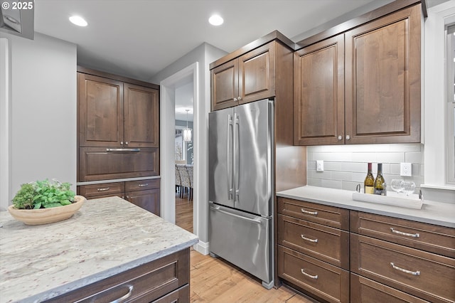 kitchen featuring recessed lighting, decorative backsplash, light wood finished floors, and freestanding refrigerator