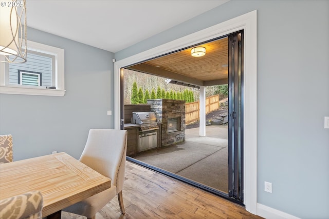 dining area featuring baseboards, a stone fireplace, and wood finished floors