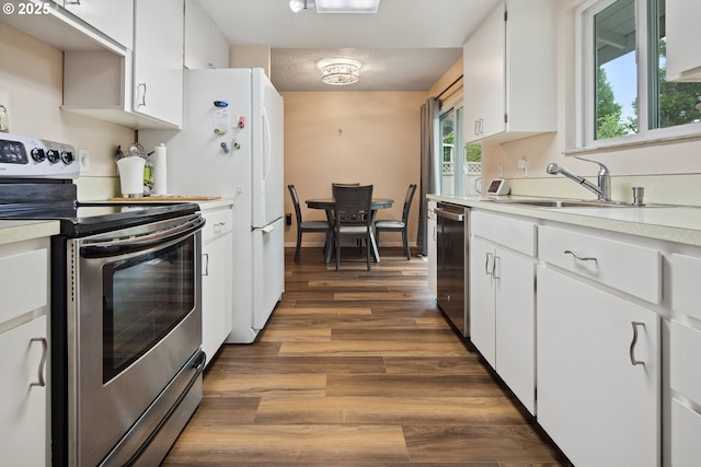 15580 SW Royalty Pkwy, Portland, OR 97224 - kitchen featuring appliances with stainless steel finishes, a sink, light countertops, wood finished floors, and white cabinets