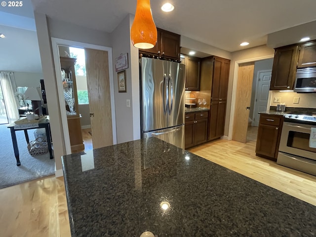2145 Rock Ledge Dr, Keizer, OR 97303 - kitchen with appliances with stainless steel finishes, light wood-style floors, dark stone counters, dark brown cabinetry, and recessed lighting