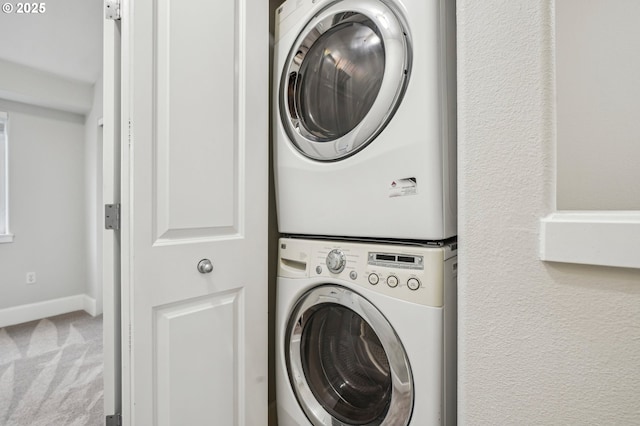 washroom with stacked washing maching and dryer and carpet flooring