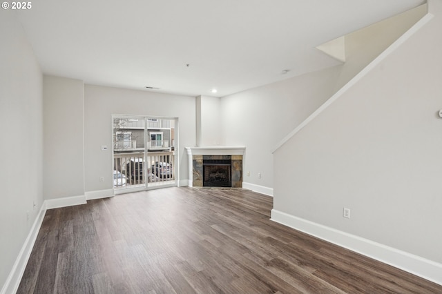 unfurnished living room featuring a tiled fireplace and dark hardwood / wood-style floors