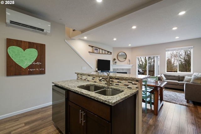 kitchen featuring an AC wall unit, light stone counters, dark hardwood / wood-style floors, sink, and stainless steel dishwasher