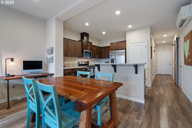 dining area featuring a barn door, a wall mounted air conditioner, and dark hardwood / wood-style flooring