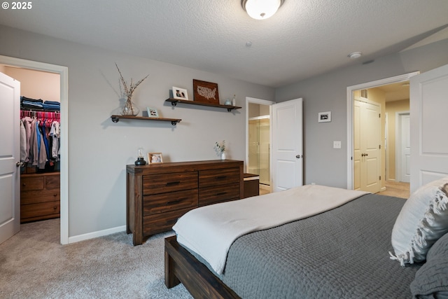 bedroom featuring a textured ceiling, light colored carpet, a spacious closet, and a closet