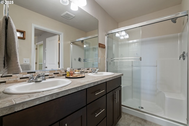 bathroom with tile patterned flooring, backsplash, walk in shower, and vanity