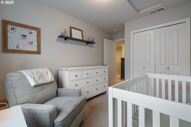 carpeted bedroom with a textured ceiling, a closet, and a nursery area