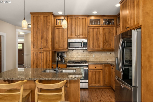 17760 SW Robert Ln, Beaverton, OR 97078 - kitchen with stainless steel appliances, brown cabinetry, decorative backsplash, glass insert cabinets, and a breakfast bar area