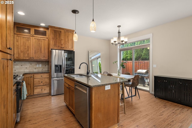 17760 SW Robert Ln, Beaverton, OR 97078 - kitchen featuring appliances with stainless steel finishes, brown cabinets, light wood finished floors, a chandelier, and backsplash