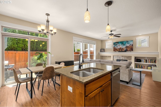 17760 SW Robert Ln, Beaverton, OR 97078 - kitchen featuring a fireplace, brown cabinetry, decorative light fixtures, light wood-style flooring, and a ceiling fan