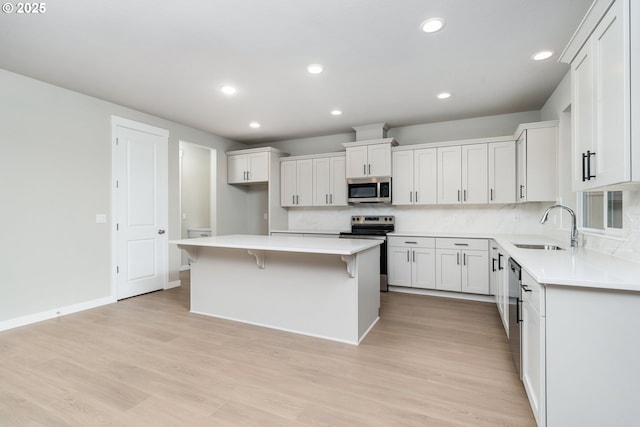 1624 NE Josephine Ct Unit 177, Estacada, OR 97023 - kitchen with stainless steel appliances, a sink, a center island, light wood finished floors, and a kitchen bar