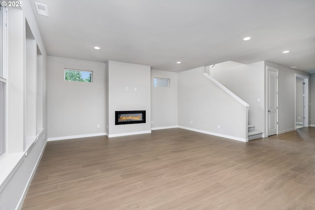 1624 NE Josephine Ct Unit 177, Estacada, OR 97023 - unfurnished living room featuring stairs, a glass covered fireplace, light wood-type flooring, recessed lighting, and baseboards