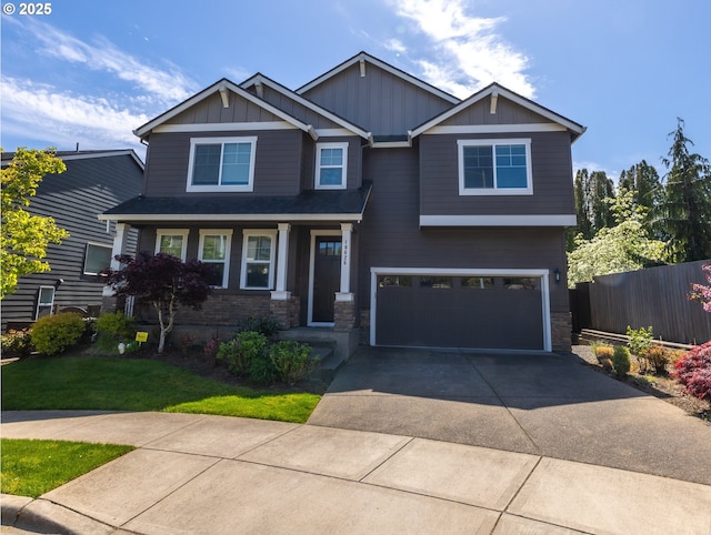 craftsman house featuring driveway, a garage, stone siding, fence, and board and batten siding