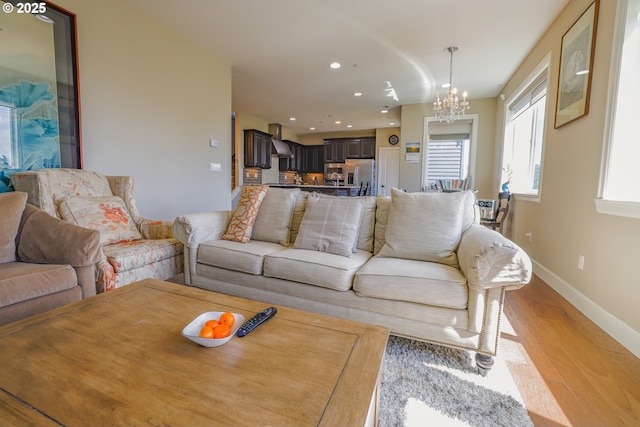 living area with light wood-style floors, baseboards, a notable chandelier, and recessed lighting