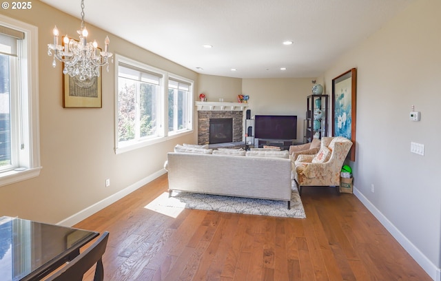 living room featuring a notable chandelier, recessed lighting, a fireplace, wood finished floors, and baseboards