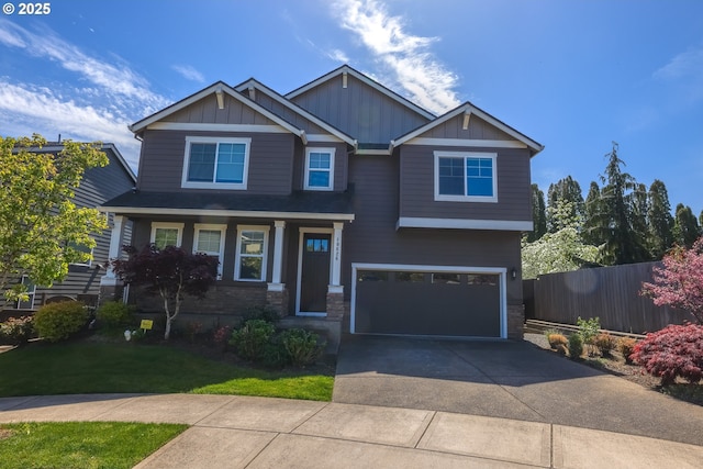 craftsman inspired home featuring concrete driveway, stone siding, an attached garage, fence, and board and batten siding