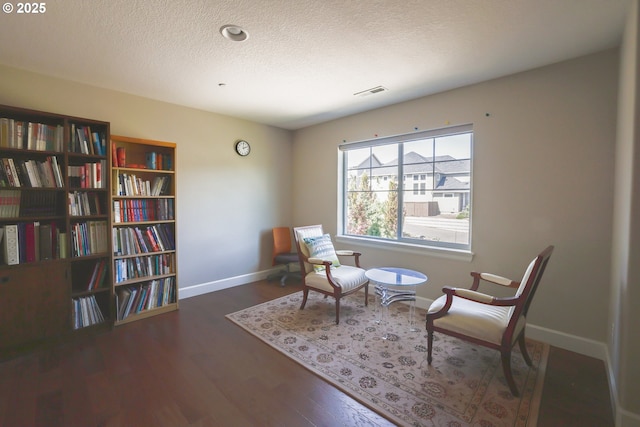 sitting room featuring a textured ceiling, wood finished floors, visible vents, and baseboards