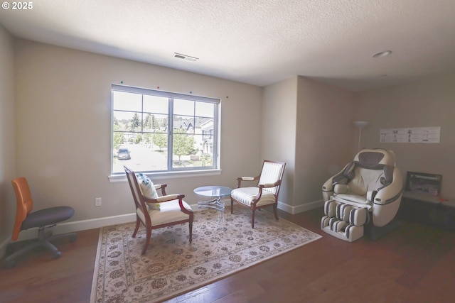 sitting room featuring a textured ceiling, wood finished floors, visible vents, and baseboards