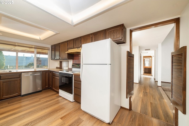 kitchen featuring electric stove, white refrigerator, light hardwood / wood-style floors, stainless steel dishwasher, and a raised ceiling