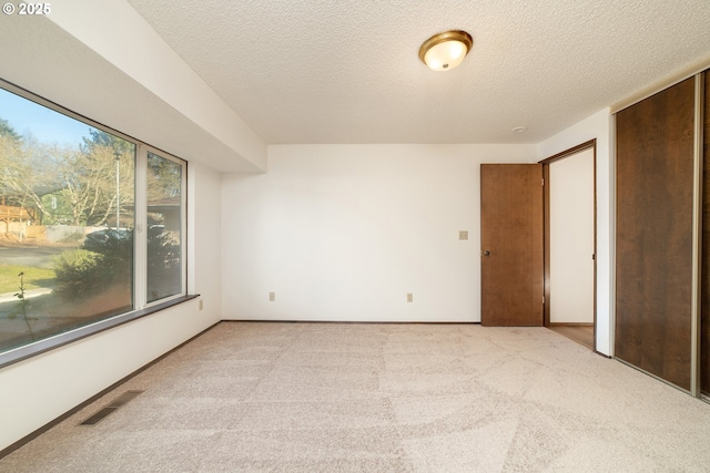 empty room with light carpet and a textured ceiling