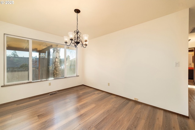 unfurnished dining area with wood-type flooring and a notable chandelier