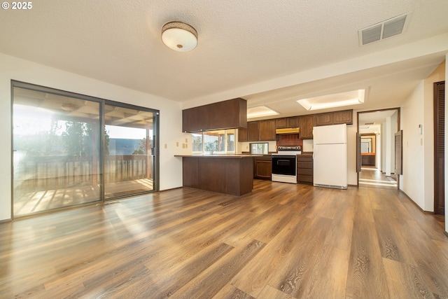 kitchen with electric range oven, white refrigerator, kitchen peninsula, dark wood-type flooring, and a textured ceiling