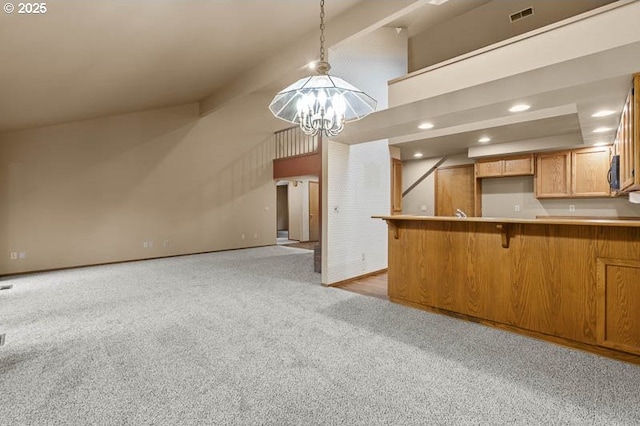 kitchen featuring pendant lighting, a kitchen bar, light carpet, an inviting chandelier, and kitchen peninsula