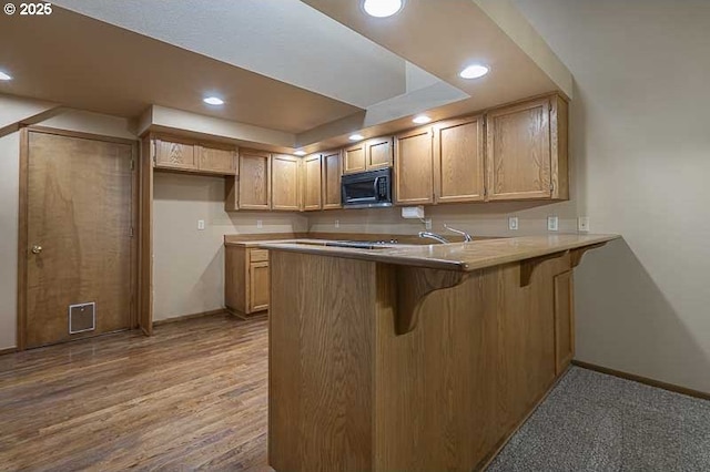 kitchen featuring a breakfast bar, light brown cabinets, and kitchen peninsula