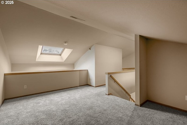 additional living space featuring light colored carpet and vaulted ceiling with skylight