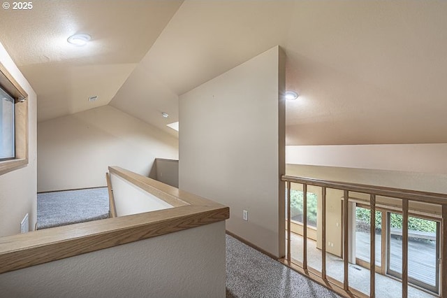 corridor with carpet flooring and vaulted ceiling