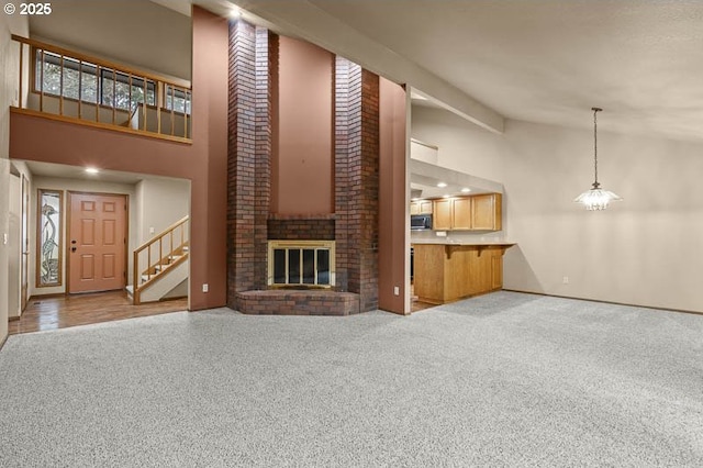 unfurnished living room with a brick fireplace, carpet flooring, a high ceiling, and an inviting chandelier