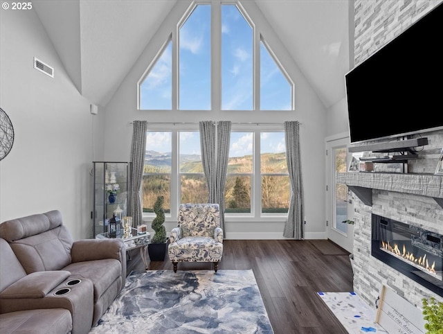 living room featuring dark hardwood / wood-style flooring, a fireplace, and high vaulted ceiling