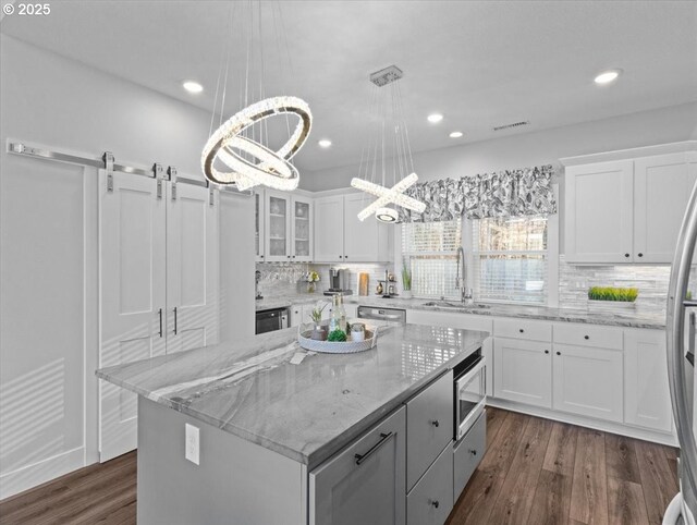 kitchen featuring white cabinetry, stainless steel appliances, a center island, and sink