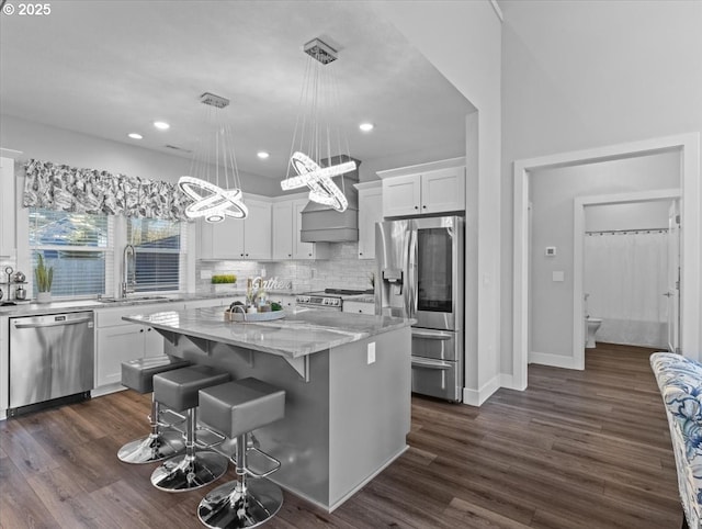 kitchen with sink, a center island, hanging light fixtures, appliances with stainless steel finishes, and white cabinets