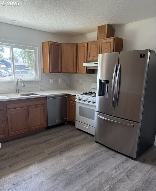 1640 Manor Dr, Gladstone, OR 97027 - kitchen featuring stainless steel appliances, a sink, wood finished floors, light countertops, and under cabinet range hood