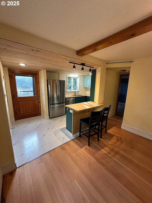 564566 Alameda Ave, Astoria, OR 97103 - kitchen with stainless steel appliances, a sink, baseboards, a peninsula, and beamed ceiling