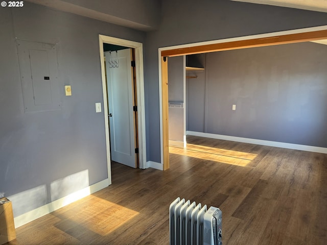 564566 Alameda Ave, Astoria, OR 97103 - unfurnished bedroom with radiator heating unit, electric panel, wood finished floors, a closet, and lofted ceiling
