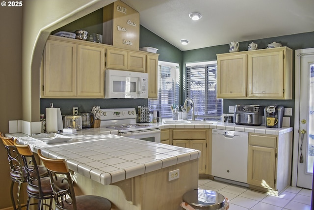 kitchen with light tile patterned flooring, tile countertops, lofted ceiling, sink, and white appliances