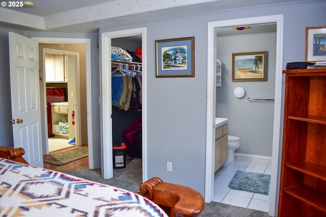 bedroom featuring connected bathroom, a spacious closet, a closet, and light tile patterned floors