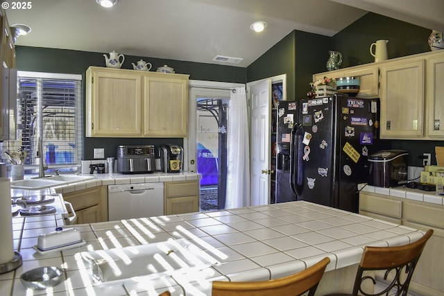 kitchen with light brown cabinetry, fridge with ice dispenser, tile countertops, vaulted ceiling, and white dishwasher