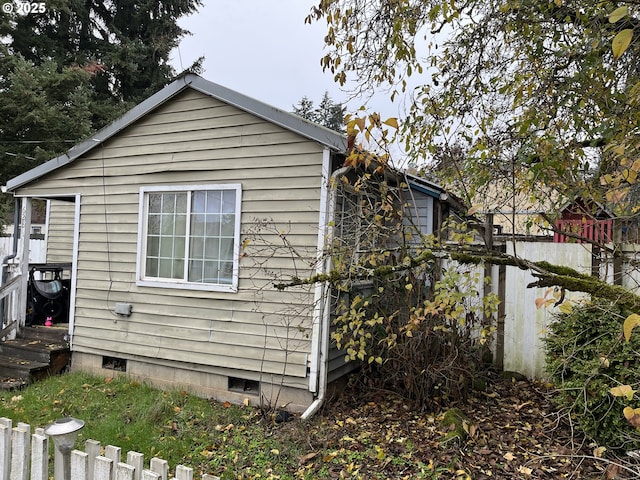 view of side of home featuring crawl space and fence