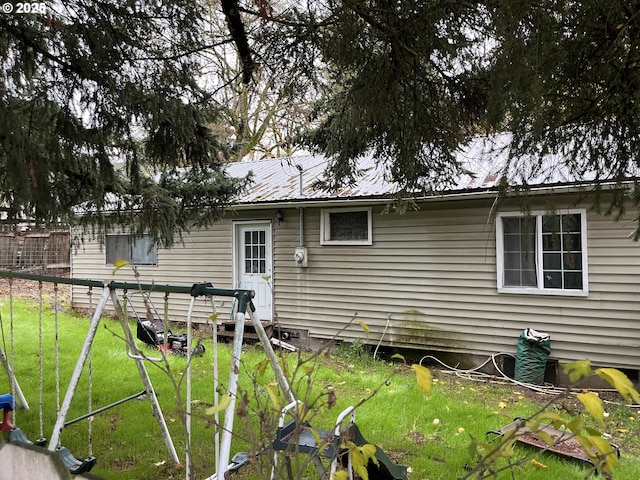 rear view of house featuring a yard and metal roof