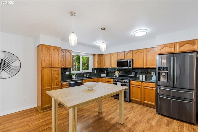 kitchen with dark countertops, appliances with stainless steel finishes, tasteful backsplash, and a sink