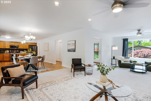 living room with recessed lighting, baseboards, and ceiling fan with notable chandelier