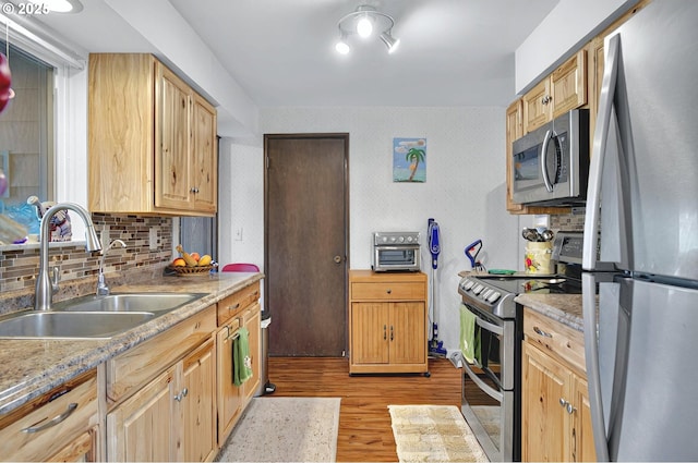 kitchen with decorative backsplash, appliances with stainless steel finishes, light wood-type flooring, a sink, and light brown cabinets