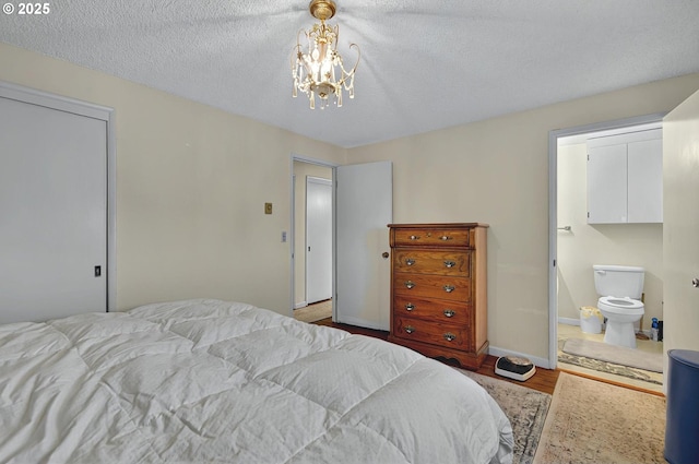 bedroom featuring an inviting chandelier, a textured ceiling, baseboards, wood finished floors, and a closet