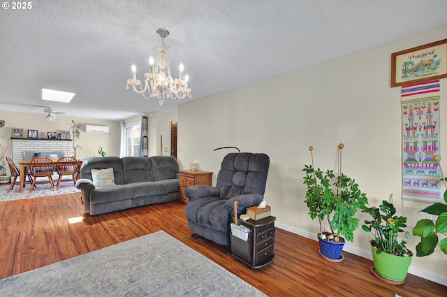 living area with a textured ceiling, baseboards, wood finished floors, and a wall mounted air conditioner